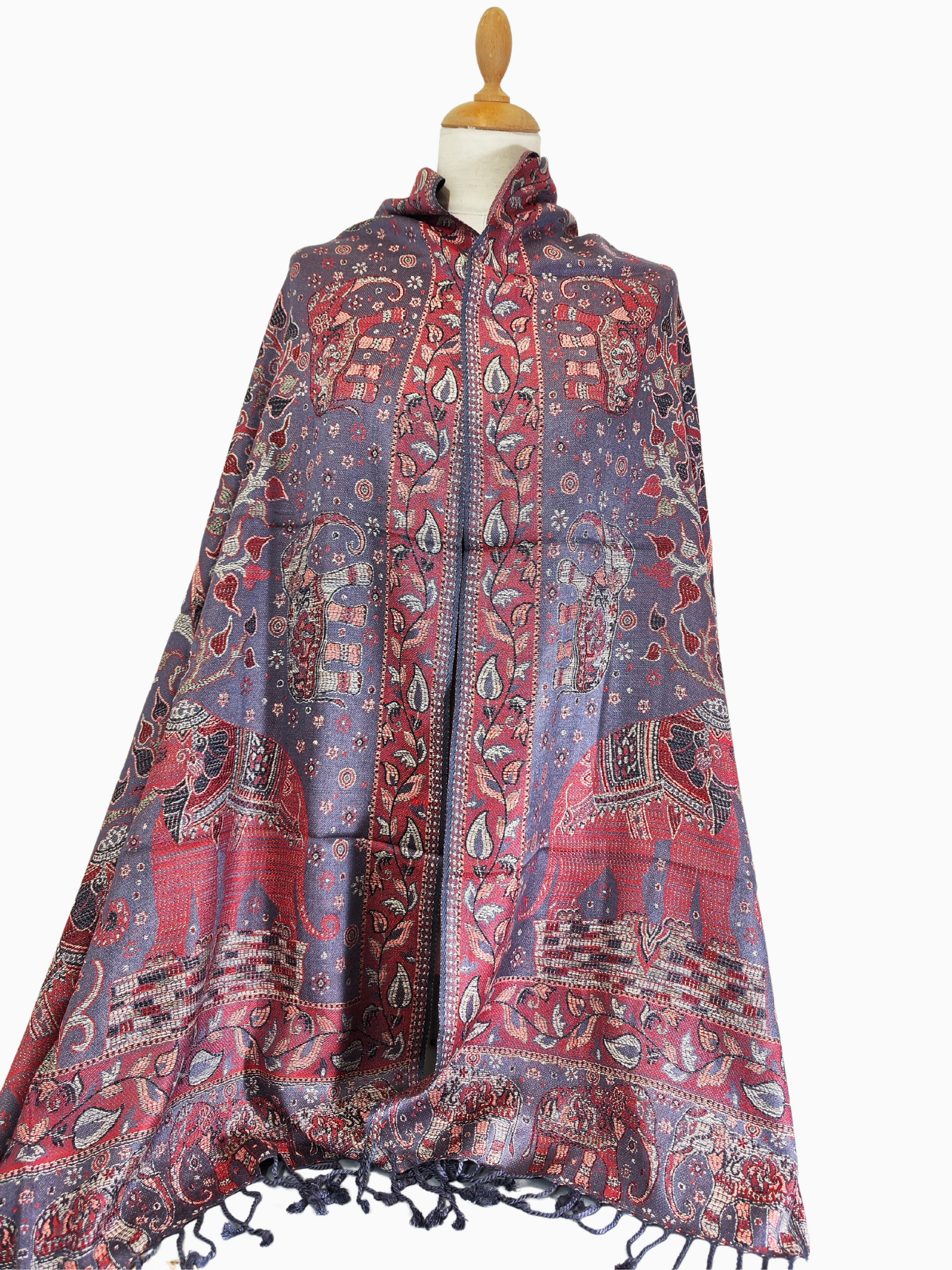Châle en pashmina au tissage complexe sur fond violet, orné de motifs éléphants et floraux rouges, dorés et bleus, et de pampilles.
Luxueux châle en pashmina avec un mélange captivant de violet, de rouge, d'or et de bleu, orné d'élégants motifs d'éléphants et de fleurs et terminé par des glands.