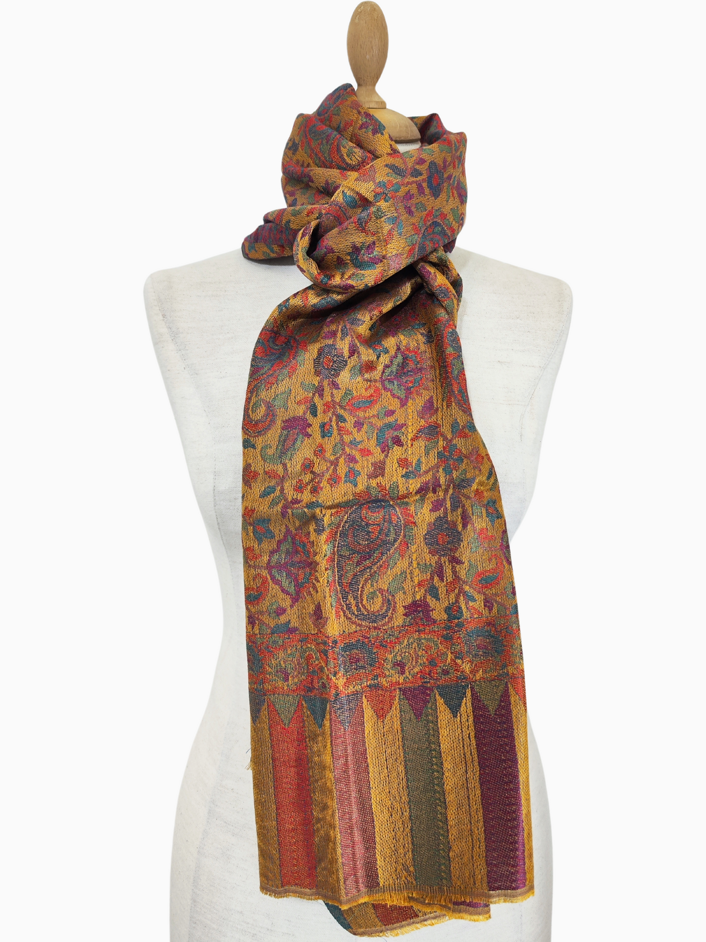 Questo splendido scialle in Pashmina misto seta è un vibrante capolavoro di artigianato tradizionale. Il tessuto, una lussuosa combinazione tra il calore della pashmina e la lucentezza della seta, si drappeggia elegantemente e risulta eccezionalmente morbido sulla pelle. Lo scialle è prevalentemente giallo sole, che irradia calore e positività, ornato da intricati motivi paisley in ricche tonalità di rosso, blu e verde. Questi motivi senza tempo, delicatamente intrecciati, aggiungono un senso di raffinatez