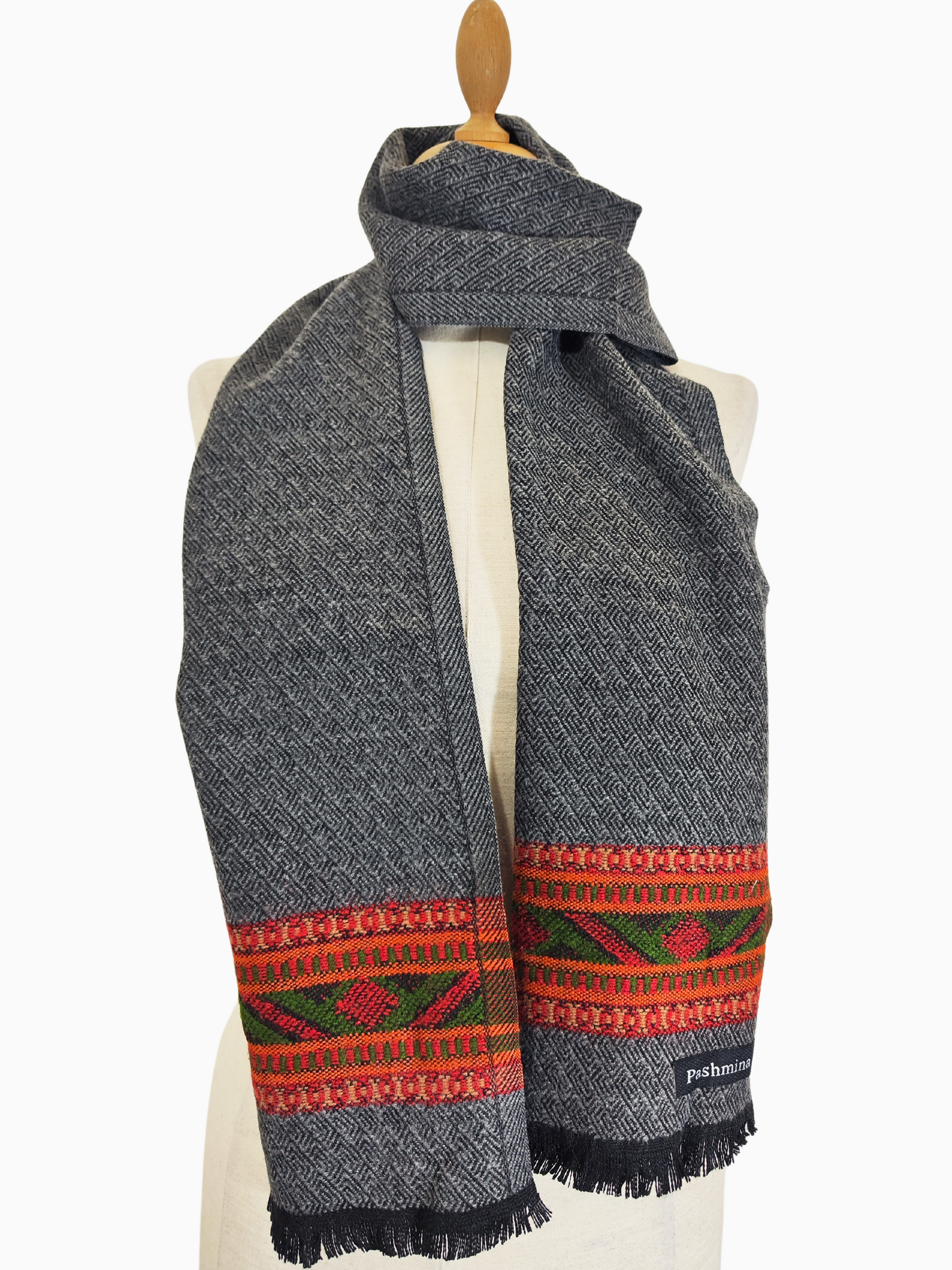 Vintage gray wool scarf featuring a handwoven tribal design in shades of red, orange, and green. The scarf has a fringe at the bottom