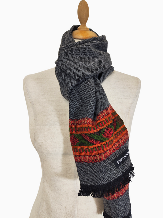 Grauer Wollschal im Vintage-Stil mit einem handgewebten Stammesmuster in Rot-, Orange- und Grüntönen. Der Schal hat eine Fransen an der Unterseite