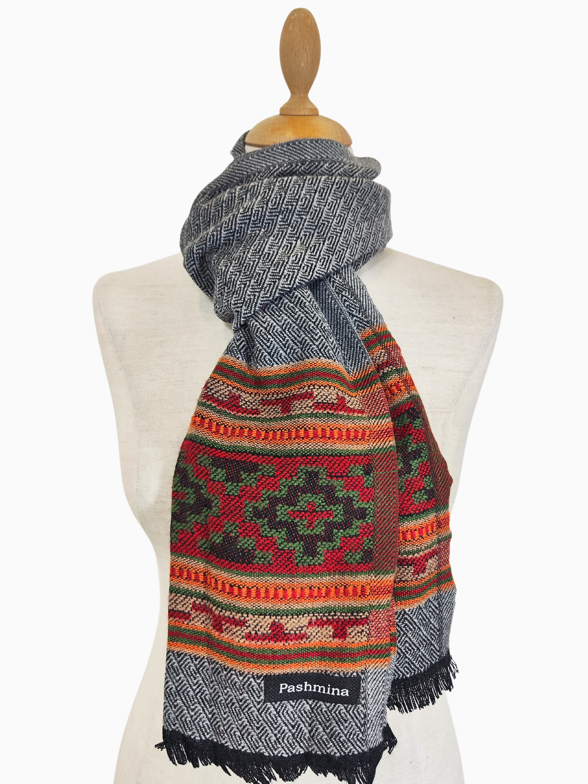 Vintage hellgrauer Pashmina-Wollschal mit buntem Stammesmuster und breiter Bordüre
Dieser Vintage-Wollschal ist eine schöne Mischung aus klassischem Stil und leuchtenden Farben. Der Hauptteil des Schals ist in einem weichen, warmen Grau gehalten, während der untere Rand ein auffälliges Muster aus bunten Dreiecken in Rot-, Orange- und Grüntönen aufweist.