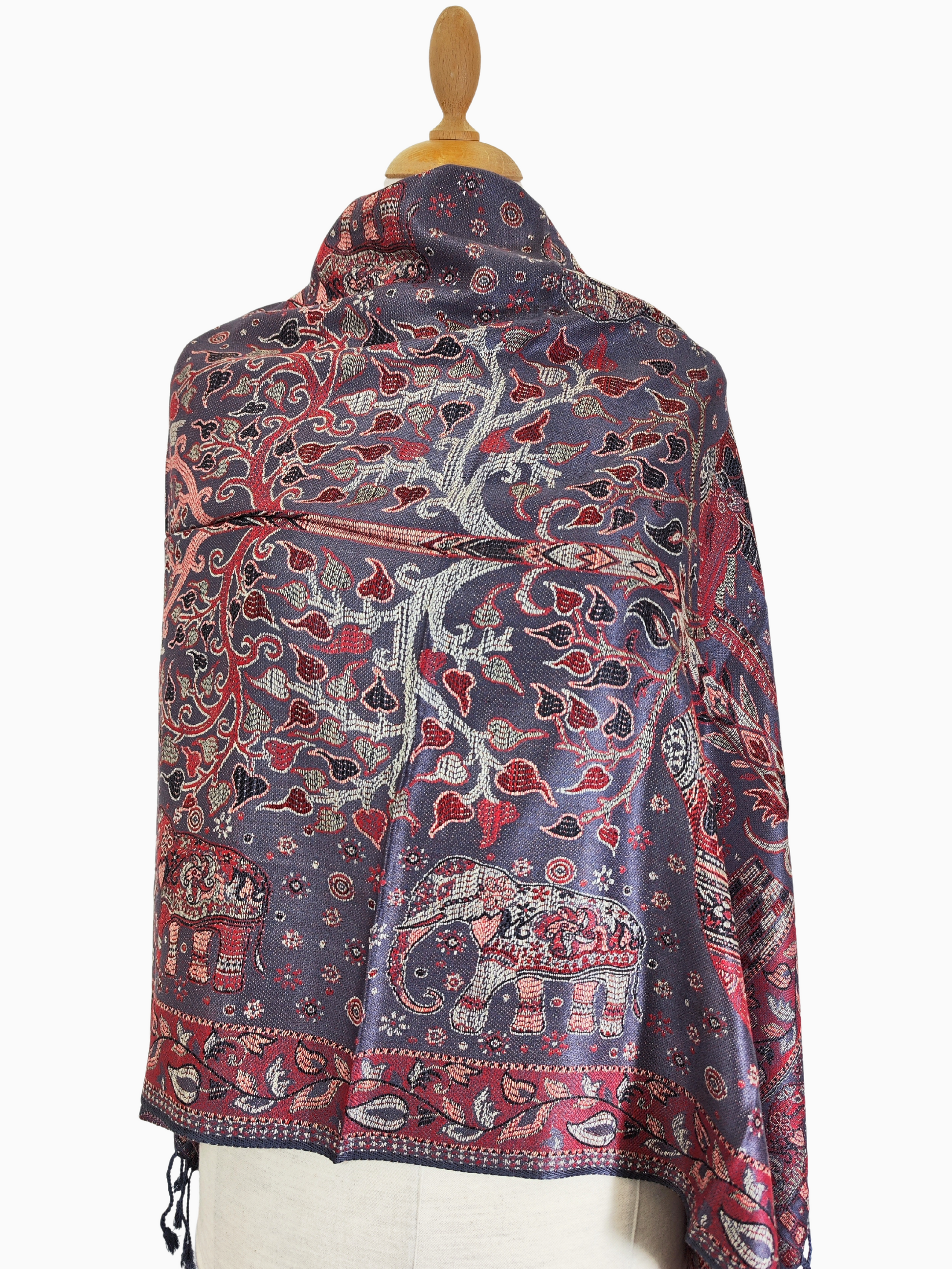 Intricately woven pashmina shawl with a purple background, featuring red, gold, and blue elephant and floral designs, and tassels.
Luxurious pashmina shawl with a captivating blend of purple, red, gold, and blue, adorned with elegant elephant and floral motifs and finished with tassels. Cashmere