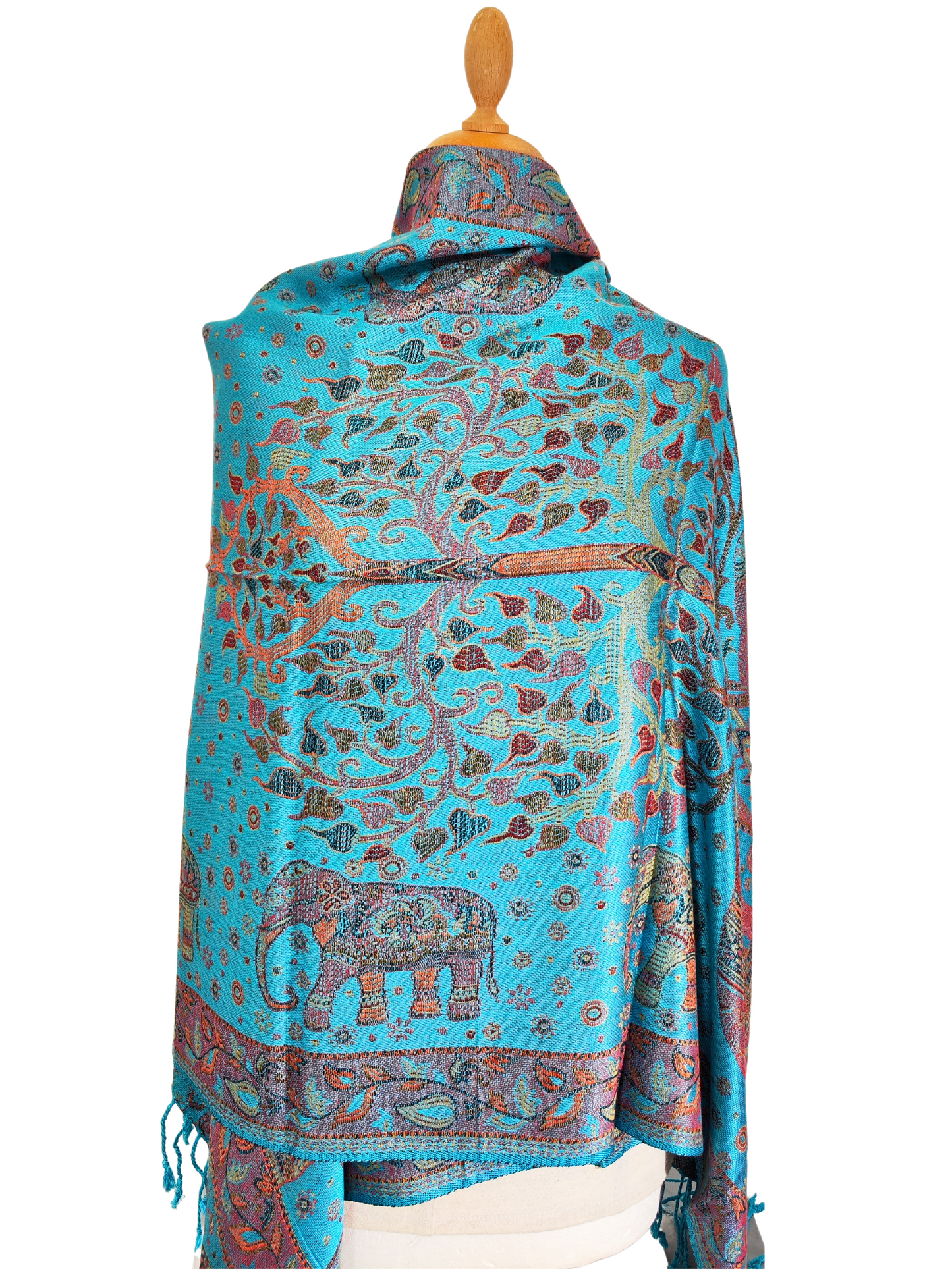 The image shows a beautiful pashmina shawl with a vibrant turquoise background and intricate elephant and floral motifs in shades of orange, pink, and blue. The shawl has tassels on the ends and appears to be made of a soft, luxurious fabric.