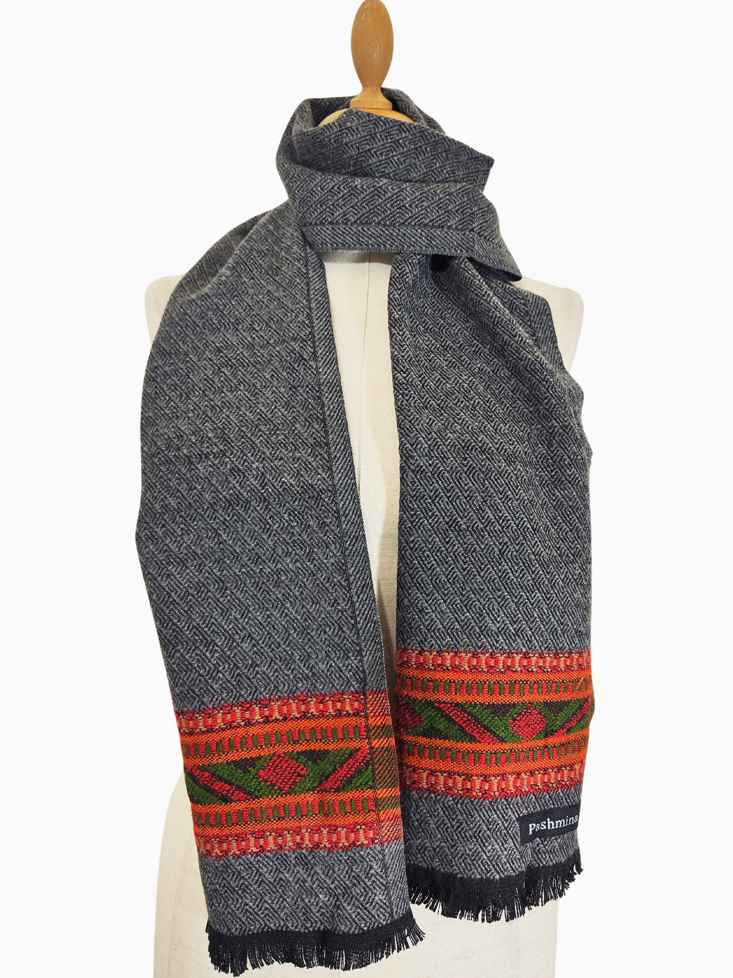 Vintage gray wool scarf featuring a handwoven tribal design in shades of red, orange, and green. The scarf has a fringe at the bottom 