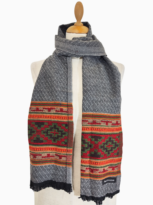 Écharpe vintage en laine Pashmina gris clair avec motif tribal coloré à large bordure
Cette écharpe vintage en laine est un magnifique mélange de style classique et de couleurs vives. Le corps principal de l'écharpe est d'un gris doux et chaud, tandis que le bord inférieur présente un motif frappant de triangles colorés dans des tons de rouge, d'orange et de vert.