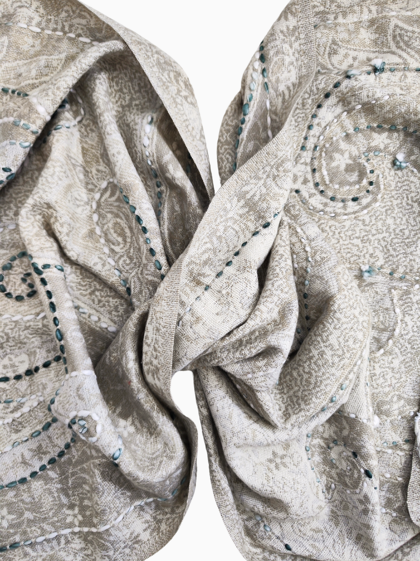 A luxurious reversible shawl made from beige lamb wool, adorned with detailed white paisley embroidery and sparkling green bead accents. The design features soft fringed edges, adding a touch of elegance. Versatile for both casual and formal wear, the shawl is displayed on a mannequin to highlight its intricate craftsmanship and lightweight drape. Perfect for layering or as a statement accessory.